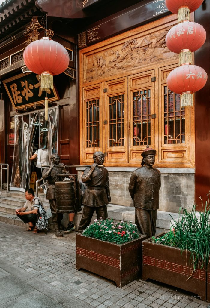 Historisches Haus in Peking mit roten Lampions und Bronzefiguren. 