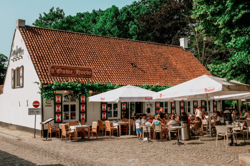 Außenfassade eines Restaurants  mit Terrasse, Schirmen, Bestuhlung und Gästen in Deurle. 
