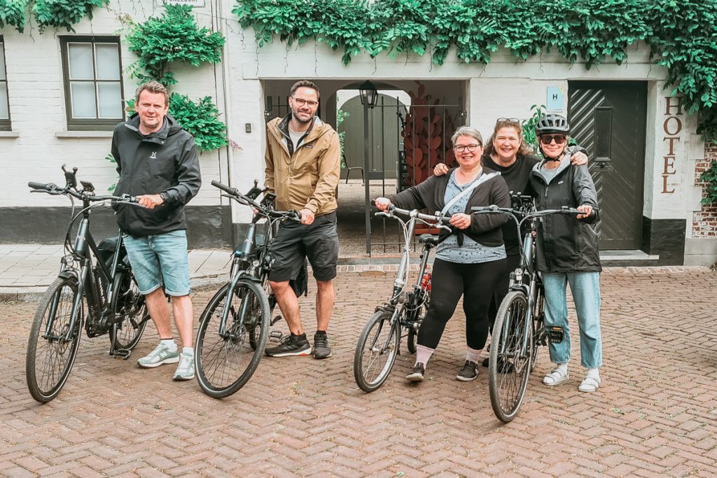 Menschen mit E-Bikes vor Fassade des Hotel Nenuphar an der Leie. 