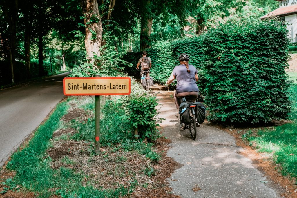 Fahrradweg und Radfahrer am Ortseingang von Sint-Martens-Latem. 