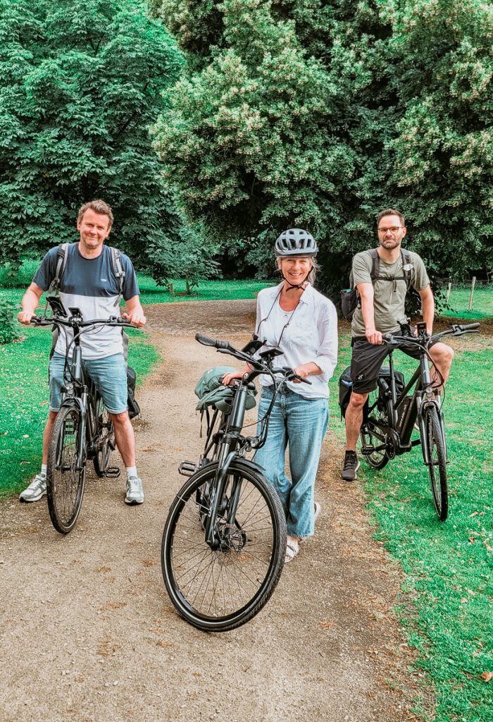 Drei Menschen auf E-Bikes, unterwegs in der Leie-Region. 