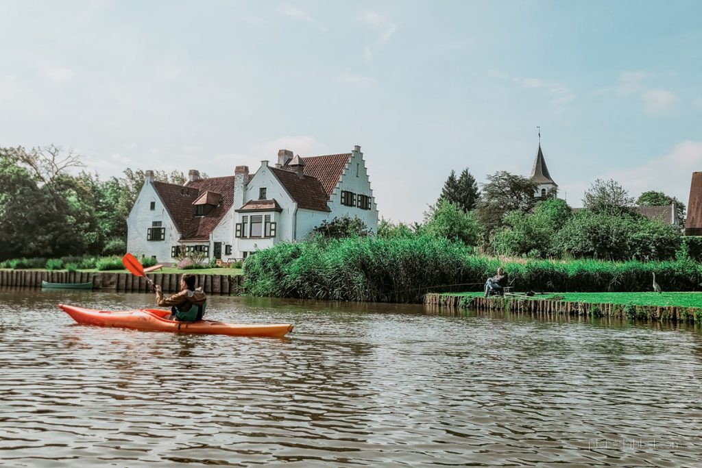 Kanufahrer auf der Leie. Im Hintergrund eine weiße Villa. 