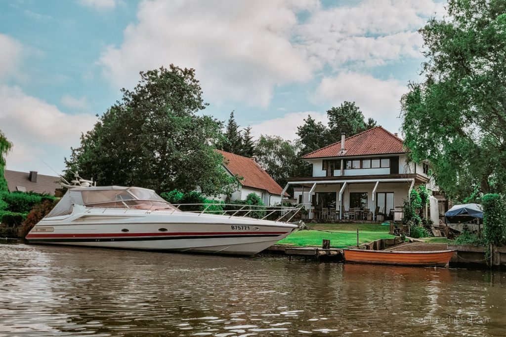Villa mit Motorboot und Ruderboot vom Wasser aus betrachtet. 