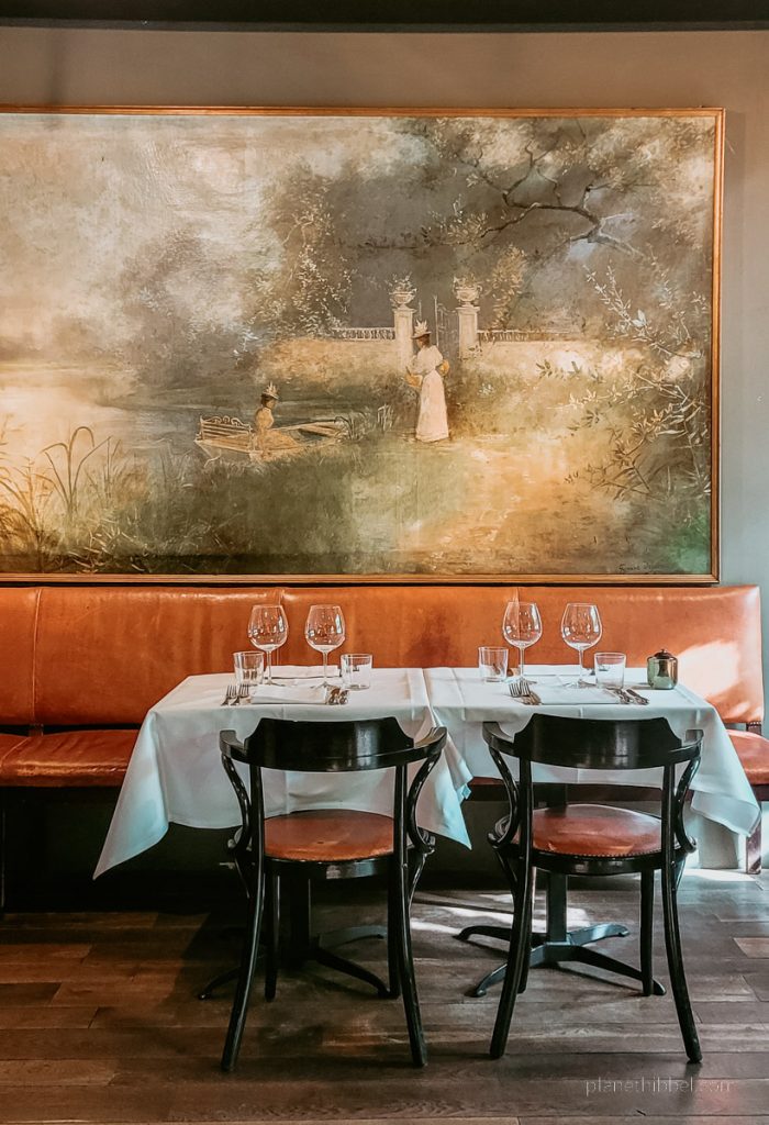 Innenraum mit Tisch, Stühlen und Bild der Leie-Region im Restaurant Nenuphar. 