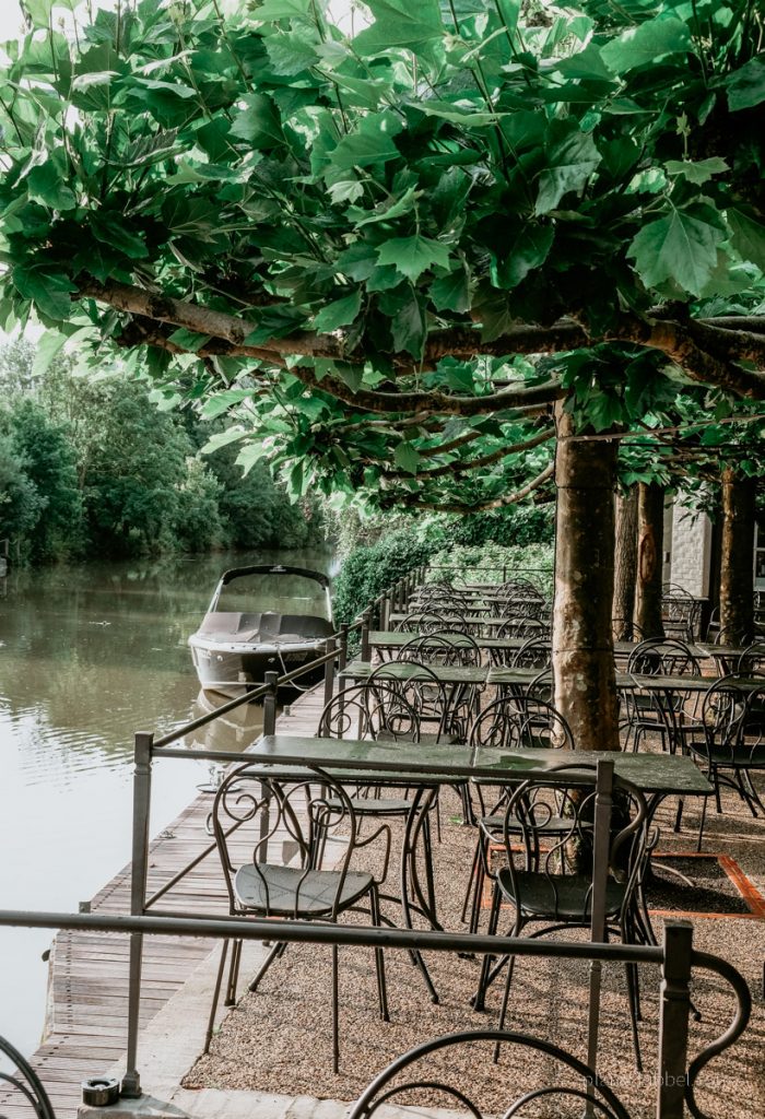 Außenterrasse dess Restaurant Nenuphar mit Blick auf Steg, Boot und den Fluss Leie.