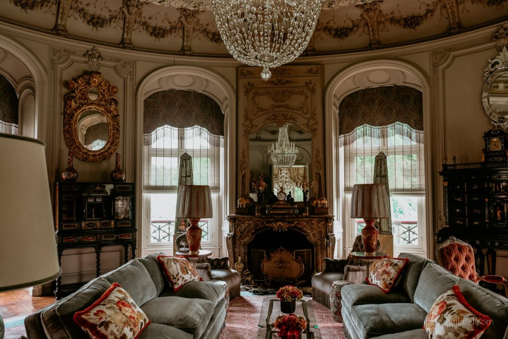 Pompöses Wohnzimmer mit Kronleuchter, Sofas, Kissen, Spiegeln und Kamin im Schloss Ooidonk.  